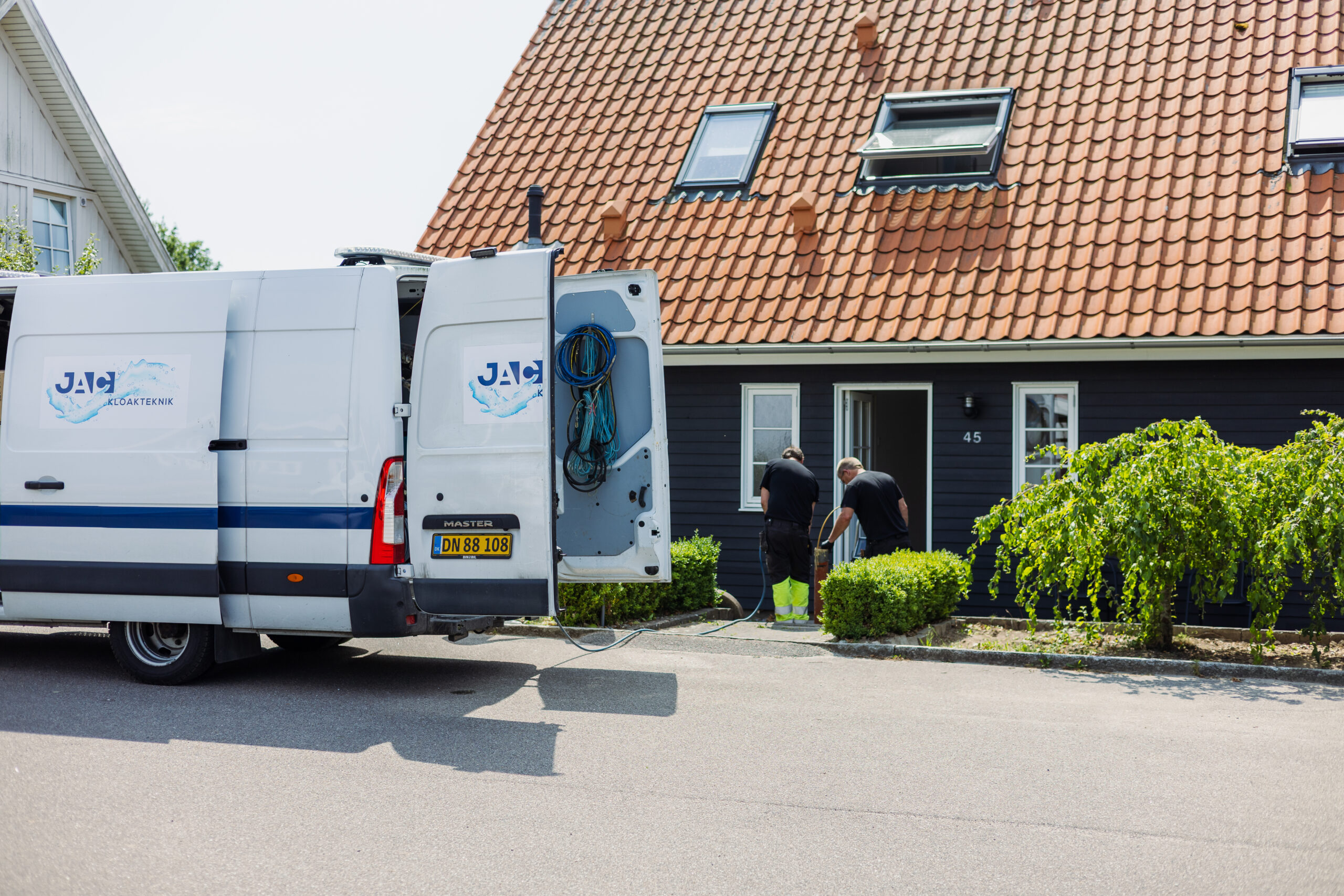 JAC Kloakteknik servicebil og medarbejdere foran hus