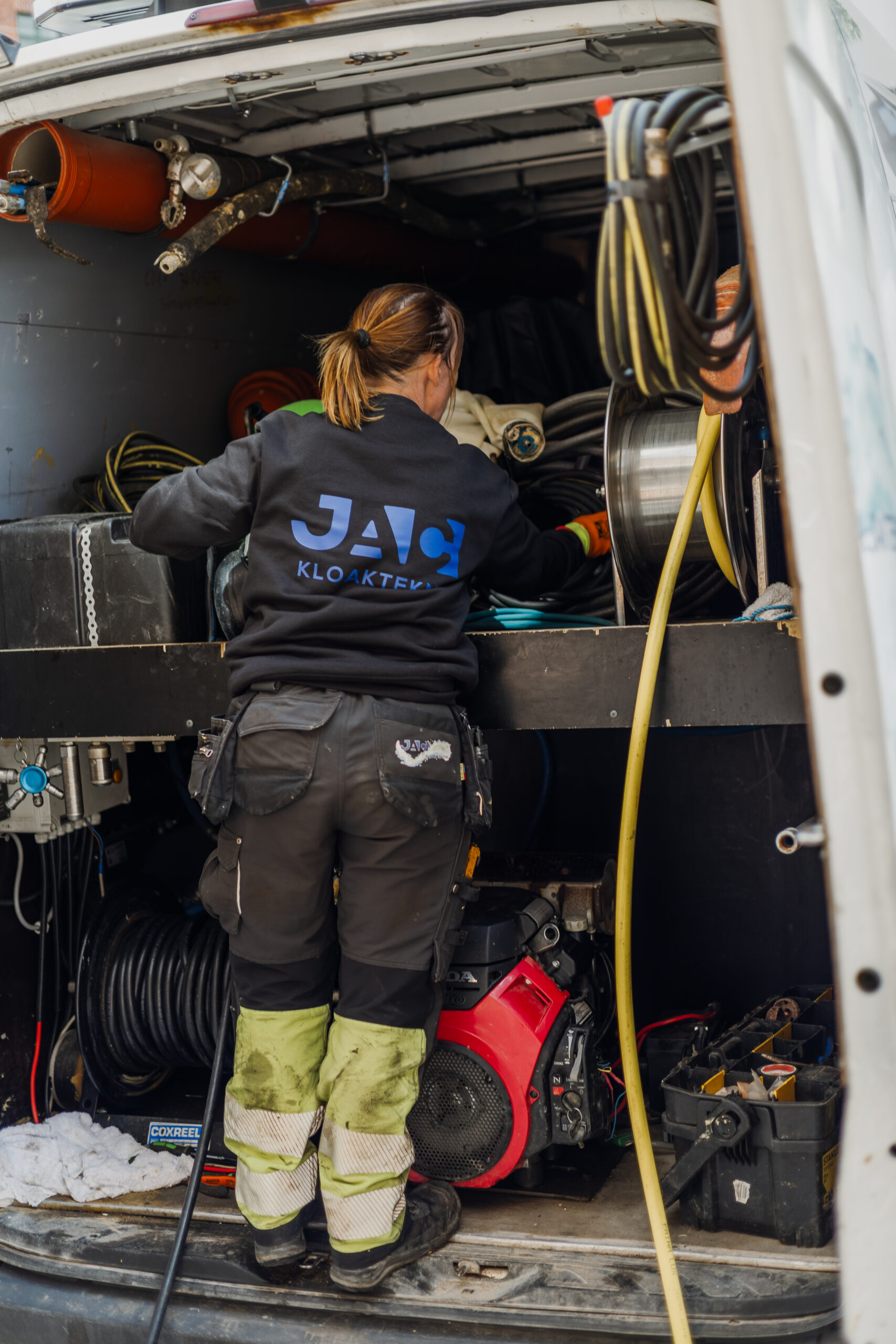 Kvinde fra kloakfirma arbejder med udstyr i servicevogn